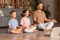 Dad with child little son and daughter doing yoga online, sitting in lotus pose on floor and meditating with closed eyes Royalty Free Stock Photo