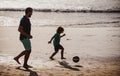 Dad and child playing outdoor, silhouette on sunset. Father and son play soccer or football on the beach on summer Royalty Free Stock Photo