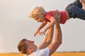 Dad and child playing with son together outdoors. Father throws up child