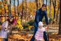 Dad and children spend time together in the autumn city park, children and parents, happy people walk and relax, girls ride Royalty Free Stock Photo