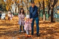 dad and children spend time together in the autumn city park, children and parents, happy people walk and relax, girls ride Royalty Free Stock Photo