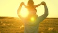 Dad dancing on his shoulders with his daughter in sun. Father travels with baby on his shoulders in rays of sunset. A Royalty Free Stock Photo