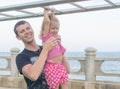 Dad and daughter playing promenade by the sea. young man, little girl hanging on the bar. Royalty Free Stock Photo