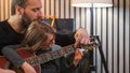 Dad and daughter plays guitar together.Little girl learning guitar with her father at home.Front view.Guitar class at Royalty Free Stock Photo