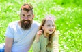 Dad and daughter sits on grass at grassplot, green background. Child and father posing with crown and bow photo booth