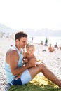 Dad feeding his little daughter sitting on the beach Royalty Free Stock Photo