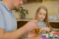 dad feeds honey from a spoon to a sick child at home, who is distracted from the disease by drawing. The father suspects