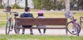 dad, girl and their bicycles at the park. Dad and girl are cyclists resting at a brown bench enjoying a happy day. Now they are