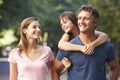 Dad Giving Daughter Piggyback On Family Walk Through Summer Park Royalty Free Stock Photo