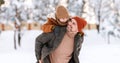 Dad giving piggyback ride to happy little son while walking outdoors in snowy winter park Royalty Free Stock Photo