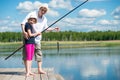 Dad helps daughter to catch fish with a fishing rod on the river Royalty Free Stock Photo