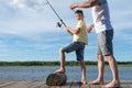 Dad helps his son to unravel the fishing line on a spinning while fishing on the lake Royalty Free Stock Photo