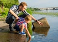 Dad helps the Little Boy to lower the paper boat to the water in Royalty Free Stock Photo