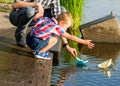 Dad helps the Little Boy to lower the paper boat to the water. D Royalty Free Stock Photo