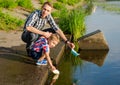 Dad helps the Little Boy to lower the paper boat to the water. Royalty Free Stock Photo