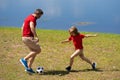 Dad with his little cute son are having fun and playing football on green grassy summer lawn. Football soccer sport Royalty Free Stock Photo