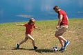 Dad with his little cute son are having fun and playing football on green grassy summer lawn. Football soccer sport Royalty Free Stock Photo