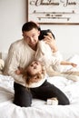 Dad and his little daughter have fun and play sitting on the bed in a bedroom with Christmas decor Royalty Free Stock Photo