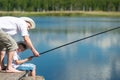 Dad with his son on the river caught a fish on a fishing pole Royalty Free Stock Photo