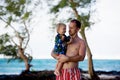 Dad, holding little toddler boy with binoculars, observing dolphins