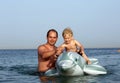 Dad holds the little boy on a toy Dolphin Royalty Free Stock Photo