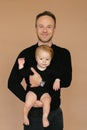 Dad holds a one-year-old daughter on a beige background. Fatherly love. Father`s day Royalty Free Stock Photo