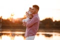 Dad hugging his little daughter near the lake on sunset. The concept of summer holiday. father`s, baby`s day. Family spending ti Royalty Free Stock Photo