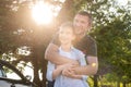 Dad hugs a cute boy standing next to a car in the woods, contour light, bright sun Royalty Free Stock Photo