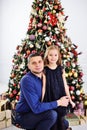 Dad hugs his little daughter in a smart dress on the background of a Christmas tree.