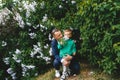 Little boy enjoys smell of blooming lilac. Dad hugs little son