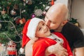 Dad kisses his son, dressed in a Santa costume, near the Christmas tree Royalty Free Stock Photo