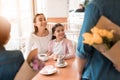 Dad and the little son are giving flowers to mother and daughter in a cafe. Royalty Free Stock Photo