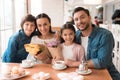 Dad and the little son are giving flowers to mother and daughter in a cafe. Royalty Free Stock Photo