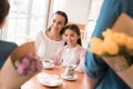 Dad and the little son are giving flowers to mother and daughter in a cafe. Royalty Free Stock Photo