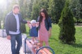 Dad and mom holding hands baby girl going by bench in park at summer. Royalty Free Stock Photo