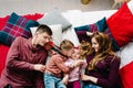 The dad, mom hug little son and daughter on bed in bedroom. Happy New Year and Merry Christmas. Top view, flatlay. The Royalty Free Stock Photo