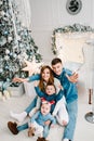 The dad, mom hug little son and daughter on floor near Christmas tree. Happy New Year and Merry Christmas. Christmas decorated Royalty Free Stock Photo