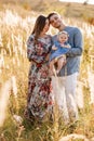 Dad, mom hugging daughter outdoors in grass on sunset. The concept of summer holiday. Mother`s, father`s, baby`s day. Family