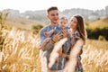 Dad, mom hugging daughter outdoors in grass on sunset. The concept of summer holiday. Mother`s, father`s, baby`s day. Family