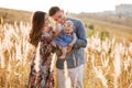 Dad, mom hugging daughter outdoors in grass on sunset. The concept of summer holiday. Mother`s, father`s, baby`s day. Family Royalty Free Stock Photo