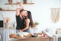 Relationship in the family with small children. Dad and mom kiss in the bright kitchen, children help to cook in the kitchen