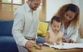 Dad, Mom and little daughter drawing with colorful pencils on paper happy smiling.Young family spend free time together in living Royalty Free Stock Photo