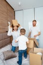 Dad mom and little son play in the bedroom with paper boxes Royalty Free Stock Photo