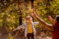 Dad playing with daughter, throw dry yellow fallen leaves. walks in autumn Park Royalty Free Stock Photo