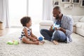 Dad playing ukulele to toddler daughter in sitting room Royalty Free Stock Photo