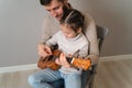 Dad plays the guitar with his daughter. The child learns to play a musical instrument with a tutor. Musical duet of a Royalty Free Stock Photo
