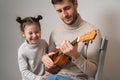 Dad plays the guitar with his daughter. The child learns to play a musical instrument with a tutor. Musical duet of a Royalty Free Stock Photo