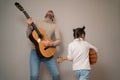 Dad plays the guitar with his daughter. The child learns to play a musical instrument with a tutor. Musical duet of a Royalty Free Stock Photo