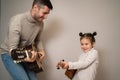 Dad plays the guitar with his daughter. The child learns to play a musical instrument with a tutor. Musical duet of a Royalty Free Stock Photo