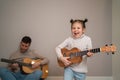 Dad plays the guitar with his daughter. The child learns to play a musical instrument with a tutor. Musical duet of a